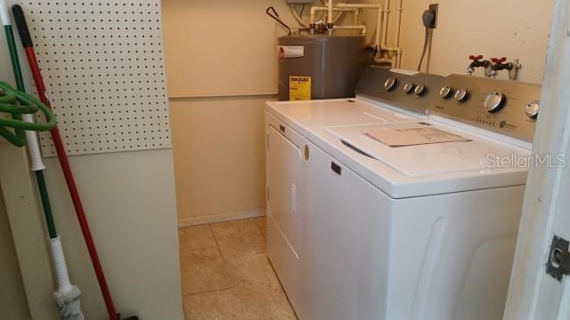 laundry area with light tile patterned flooring, separate washer and dryer, and water heater