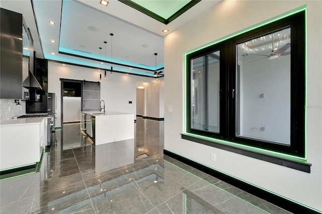 kitchen with a tray ceiling, sink, and white cabinets