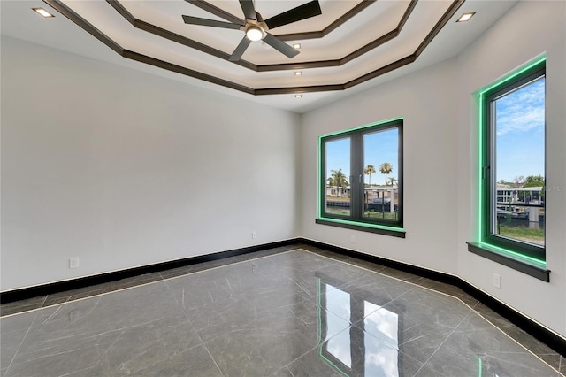 spare room featuring a tray ceiling, ceiling fan, plenty of natural light, and crown molding