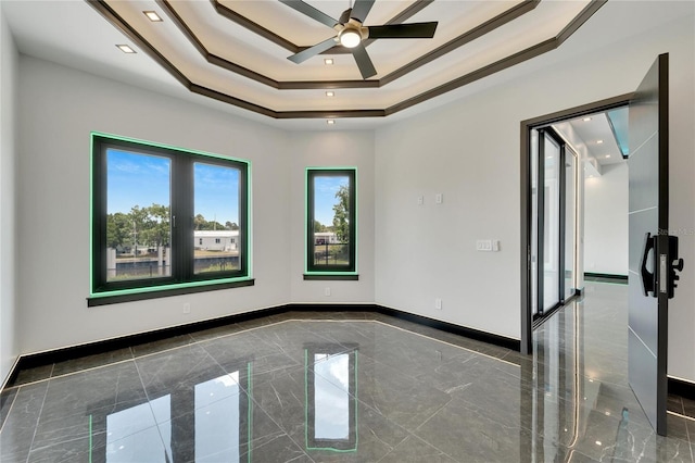 unfurnished room with ceiling fan, a raised ceiling, and ornamental molding