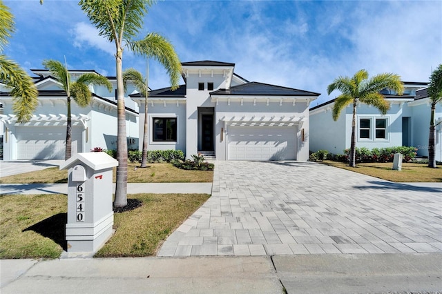 view of front of house featuring decorative driveway, an attached garage, and stucco siding