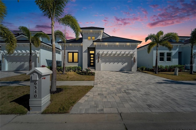 view of front facade with an attached garage, decorative driveway, and stucco siding