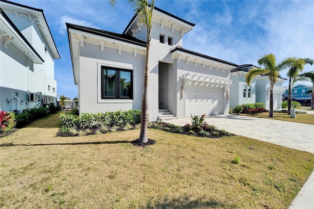 view of front of home featuring a garage, a front yard, decorative driveway, and stucco siding