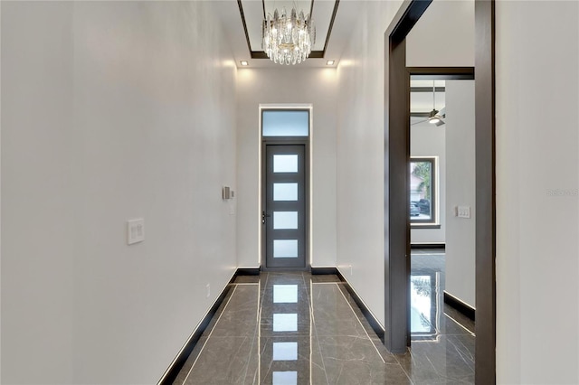 entryway with marble finish floor, baseboards, and ceiling fan with notable chandelier