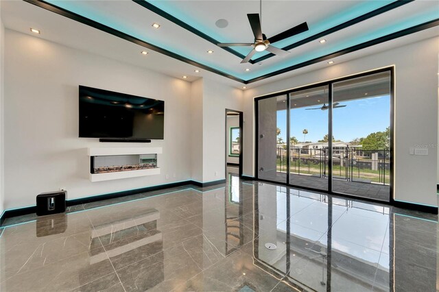 unfurnished living room with recessed lighting, a ceiling fan, baseboards, marble finish floor, and a tray ceiling