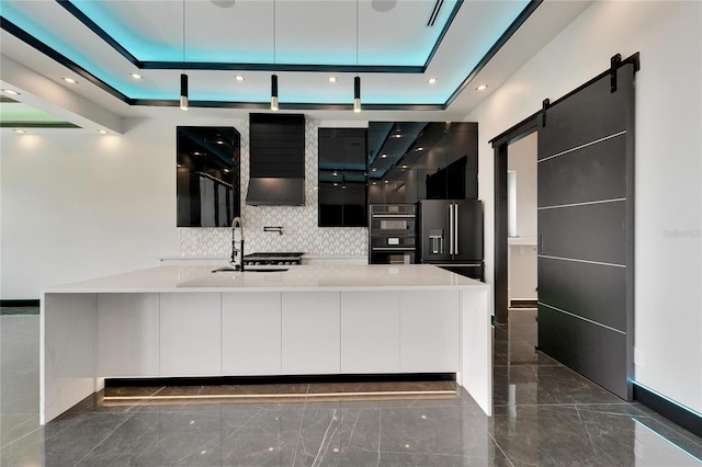 kitchen featuring a tray ceiling, high quality fridge, a barn door, and modern cabinets