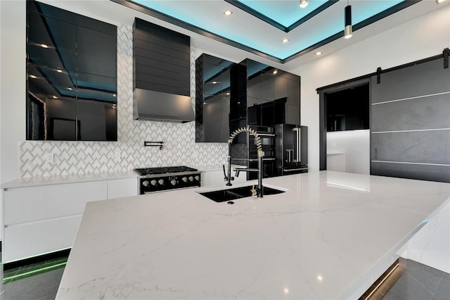 kitchen featuring premium appliances, a barn door, dark cabinets, a sink, and modern cabinets