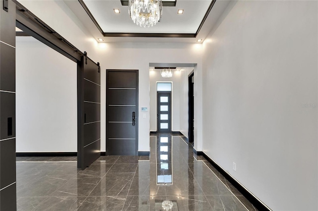 foyer featuring a chandelier, a raised ceiling, baseboards, and a barn door