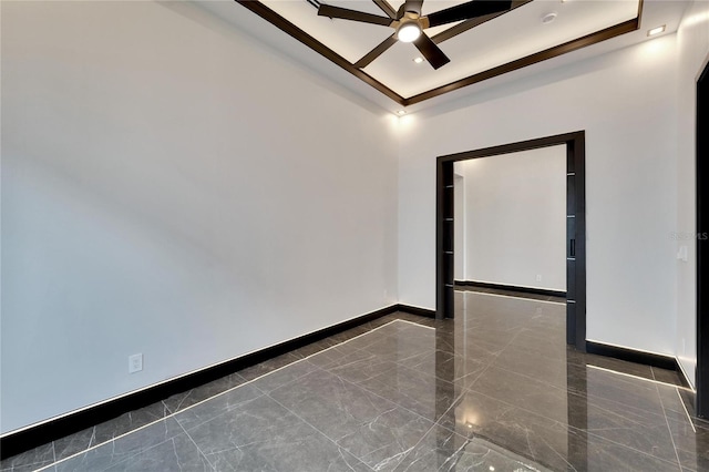 unfurnished room with a raised ceiling, ceiling fan, marble finish floor, and baseboards