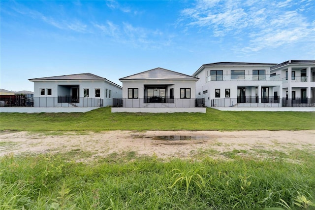 rear view of house featuring central AC unit and a lawn