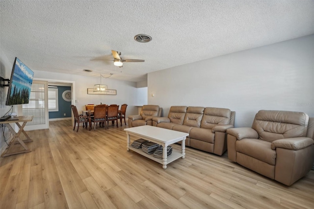 living room featuring ceiling fan, a textured ceiling, and light wood-type flooring