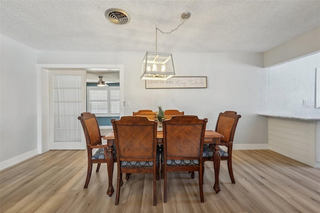 dining area with light hardwood / wood-style flooring and a textured ceiling