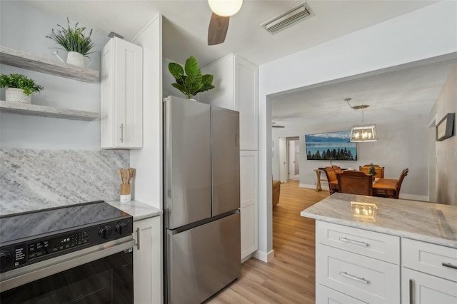 kitchen with light wood-type flooring, appliances with stainless steel finishes, decorative light fixtures, backsplash, and ceiling fan