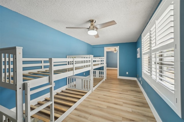 bedroom with ceiling fan, light hardwood / wood-style flooring, and a textured ceiling