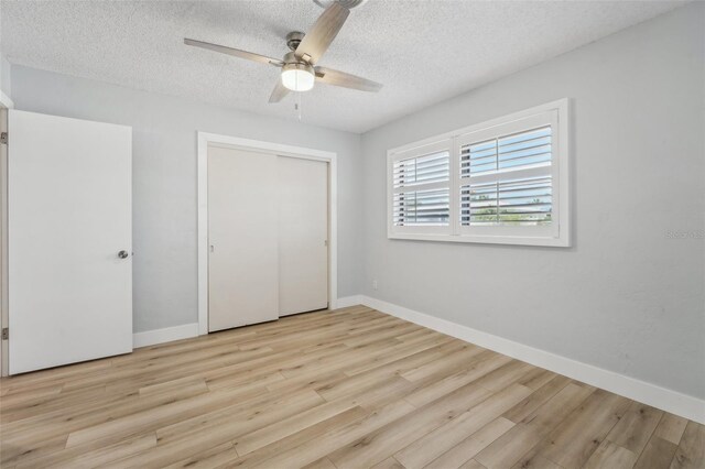 unfurnished bedroom with ceiling fan, a closet, light hardwood / wood-style flooring, and a textured ceiling