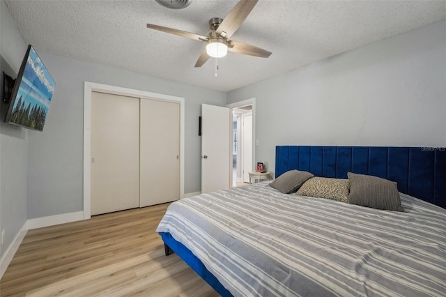 bedroom featuring ceiling fan, a closet, light hardwood / wood-style floors, and a textured ceiling