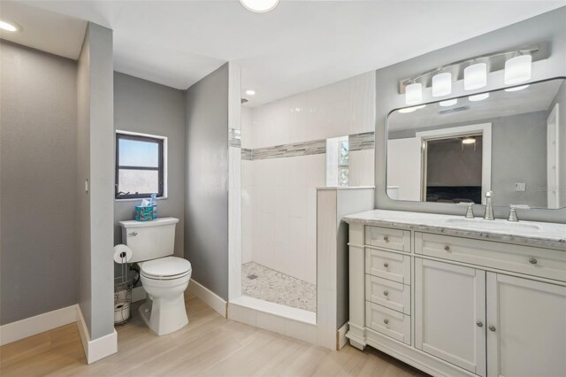 bathroom with tiled shower, vanity, and toilet