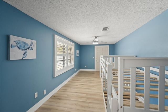 corridor featuring light hardwood / wood-style floors and a textured ceiling