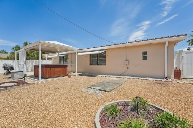 back of house with a hot tub and a patio