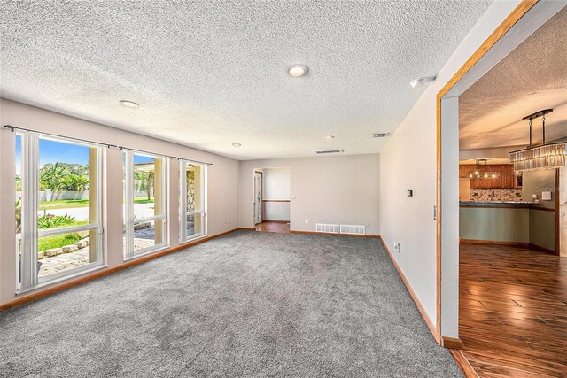 spare room featuring a textured ceiling and dark hardwood / wood-style floors