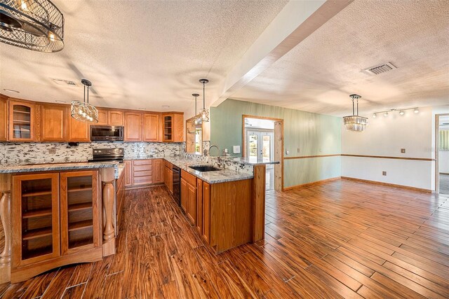 kitchen featuring kitchen peninsula, a textured ceiling, dark wood-type flooring, and sink