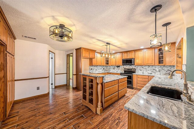 kitchen with appliances with stainless steel finishes, dark hardwood / wood-style flooring, a textured ceiling, sink, and a kitchen island