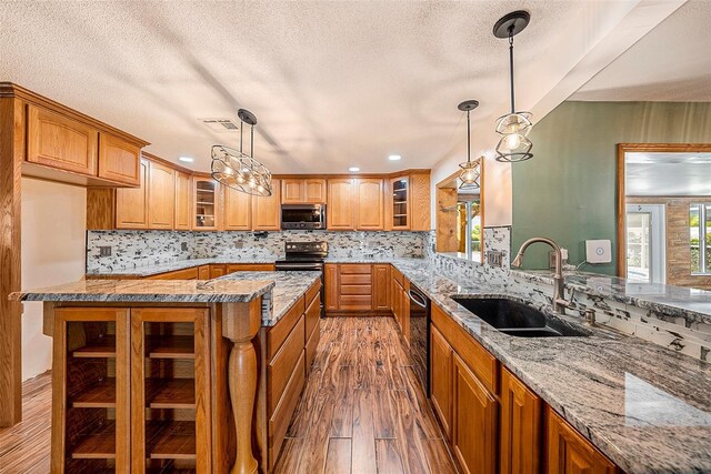 kitchen with hanging light fixtures, sink, stainless steel appliances, and hardwood / wood-style flooring