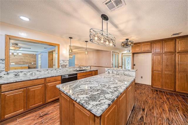 kitchen with pendant lighting, a center island, light stone countertops, a textured ceiling, and dark hardwood / wood-style flooring