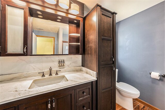 bathroom featuring backsplash, toilet, vanity, and hardwood / wood-style flooring