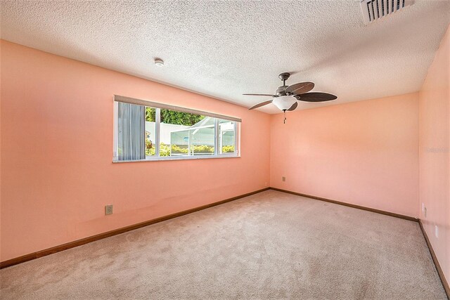 spare room with ceiling fan, light colored carpet, and a textured ceiling