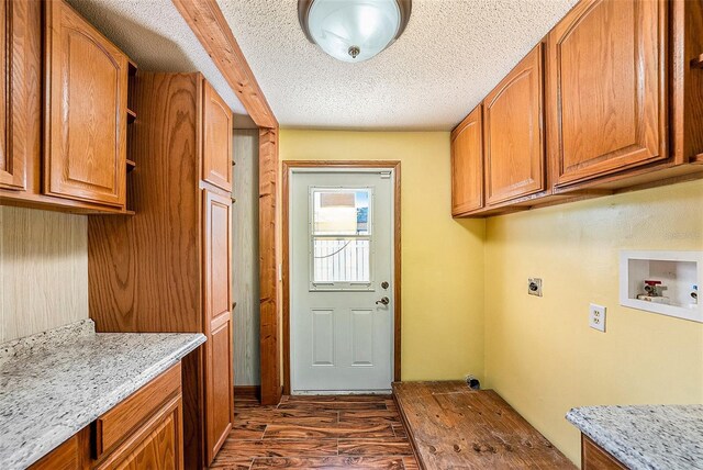 laundry area featuring cabinets, electric dryer hookup, dark hardwood / wood-style floors, hookup for a washing machine, and a textured ceiling