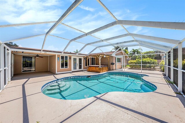 view of pool featuring french doors, ceiling fan, a lanai, a patio area, and a hot tub