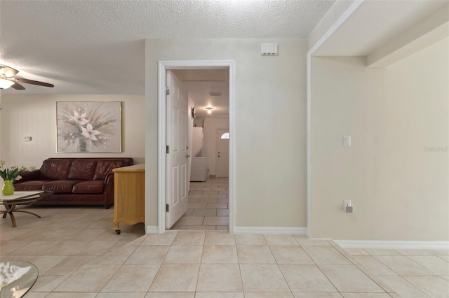 corridor featuring light tile patterned flooring and a textured ceiling