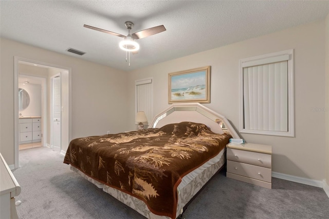 bedroom with dark colored carpet, ceiling fan, a textured ceiling, and connected bathroom