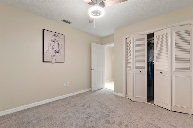 unfurnished bedroom featuring a textured ceiling, ceiling fan, light carpet, and a closet