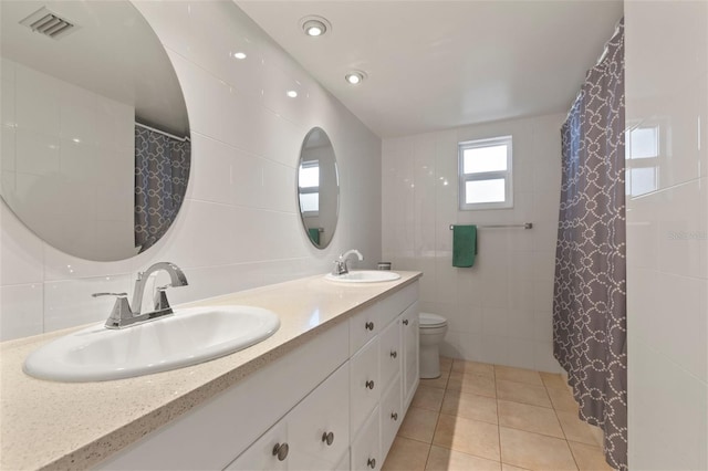 bathroom with tile patterned floors, vanity, tile walls, and toilet