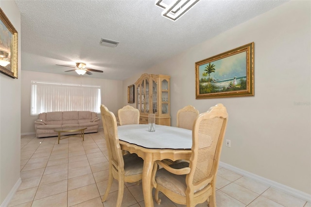 dining space featuring ceiling fan, light tile patterned flooring, and a textured ceiling