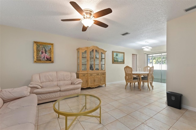 tiled living room with ceiling fan and a textured ceiling