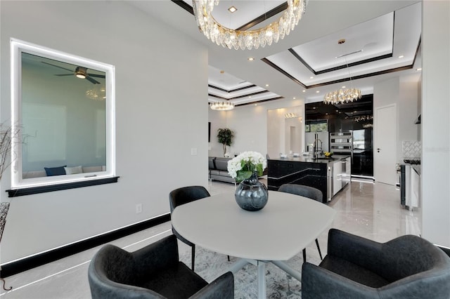 dining space featuring ceiling fan with notable chandelier and a tray ceiling