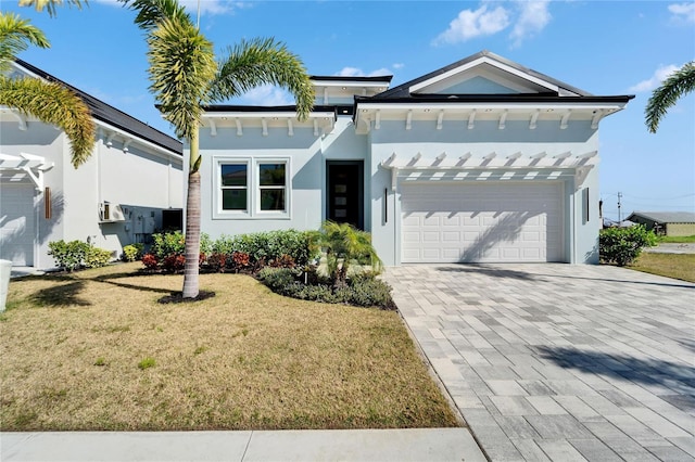 view of front of home featuring an attached garage, decorative driveway, a front yard, and stucco siding