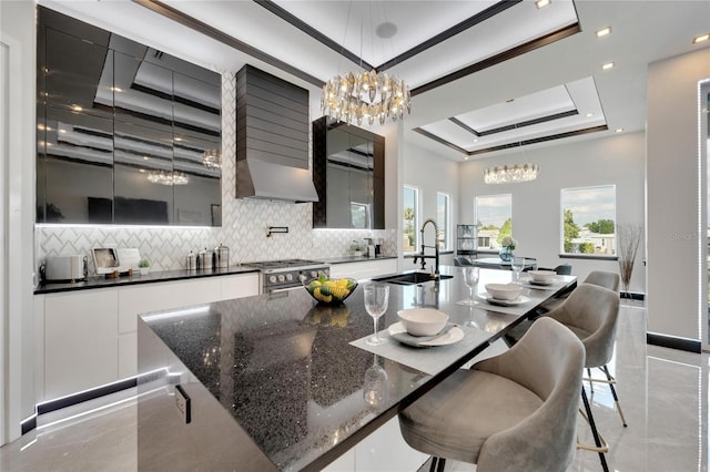 6542 Simone Shores Cir, Apollo Beach, FL 33572 - kitchen with a tray ceiling, a chandelier, modern cabinets, backsplash, and recessed lighting