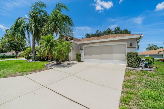 view of front of home featuring a garage, concrete driveway, a front yard, and stucco siding