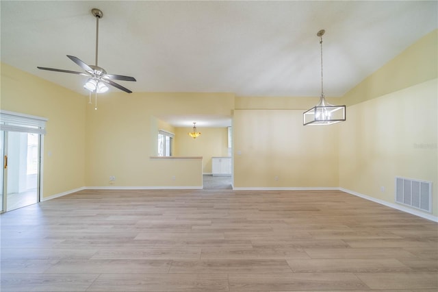 unfurnished room featuring vaulted ceiling, light wood-style flooring, visible vents, and baseboards