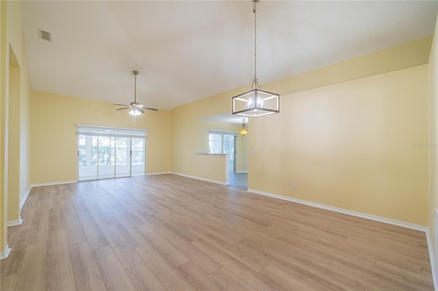 empty room featuring ceiling fan with notable chandelier, light wood finished floors, visible vents, and baseboards