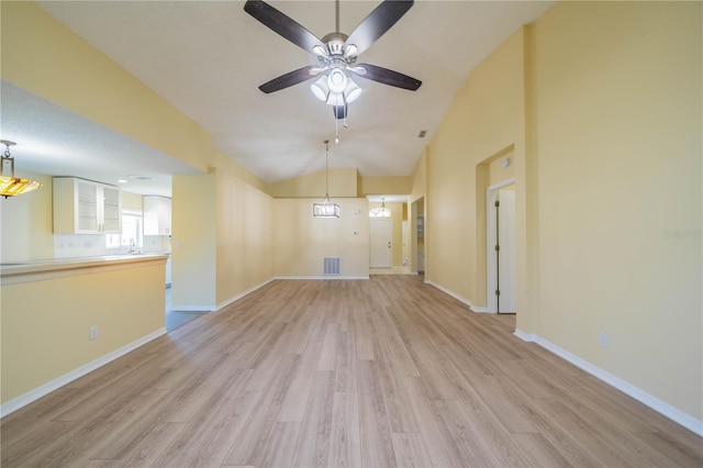 unfurnished living room featuring visible vents, vaulted ceiling, light wood-style flooring, and baseboards