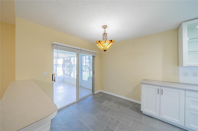 unfurnished dining area featuring a textured ceiling and baseboards