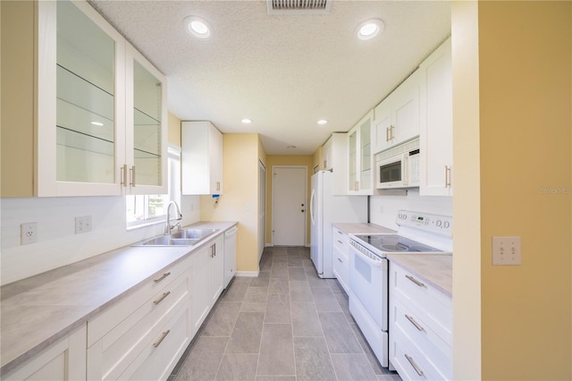 kitchen with light countertops, white appliances, a sink, and glass insert cabinets