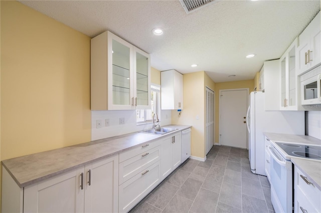 kitchen with glass insert cabinets, white cabinets, light countertops, and white appliances