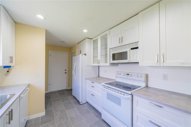 kitchen featuring white appliances, white cabinetry, glass insert cabinets, and light countertops