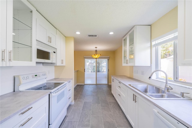 kitchen with white appliances, a sink, white cabinets, light countertops, and glass insert cabinets